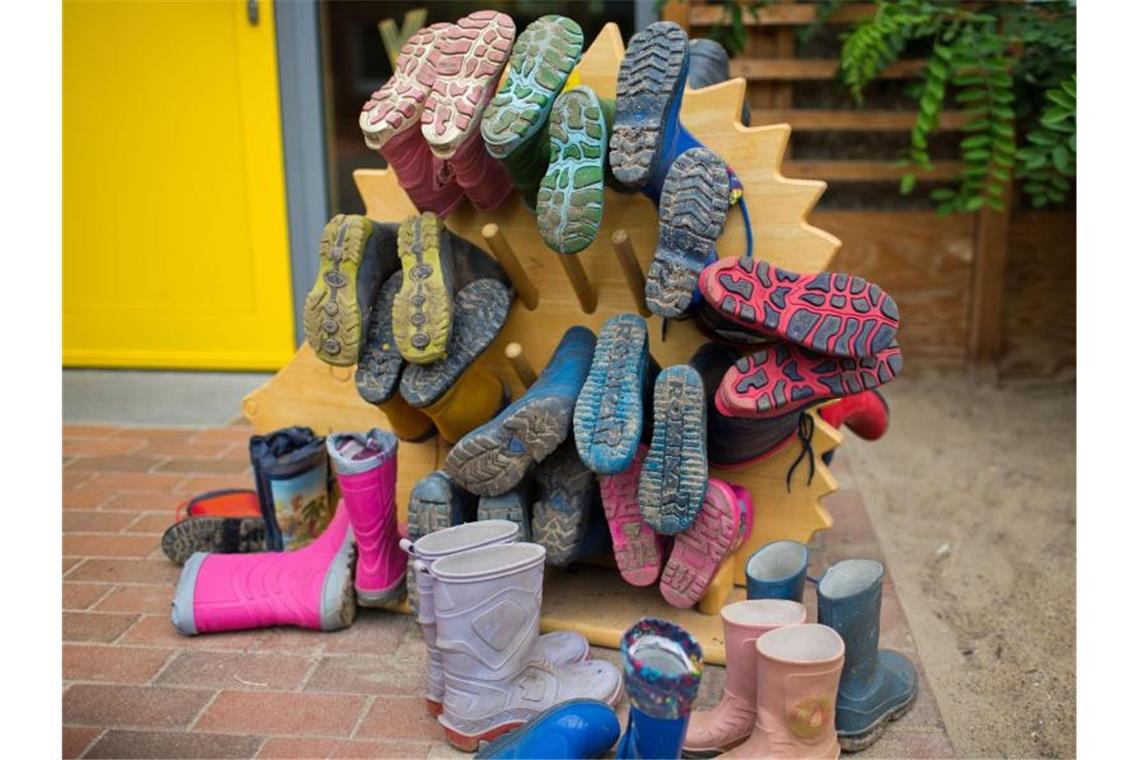 In einer Kindertagesstätte hängen Kindergummistiefel auf einer Halterung. Foto: Jens Büttner/zb/dpa/Archivbild