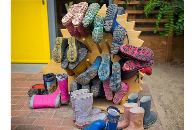 In einer Kindertagesstätte hängen Kindergummistiefel auf einer Halterung. Foto: Jens Büttner/zb/dpa/Archivbild