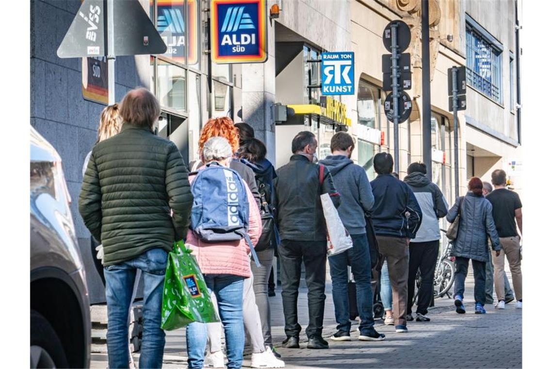 Deutsche zufrieden mit Krisenmanagement In einer langen Schlange warten Menschen auf Einlass zum Tätigen letzter Ostereinkäufe in Frankfurt. Foto: Frank Rumpenhorst/dpa