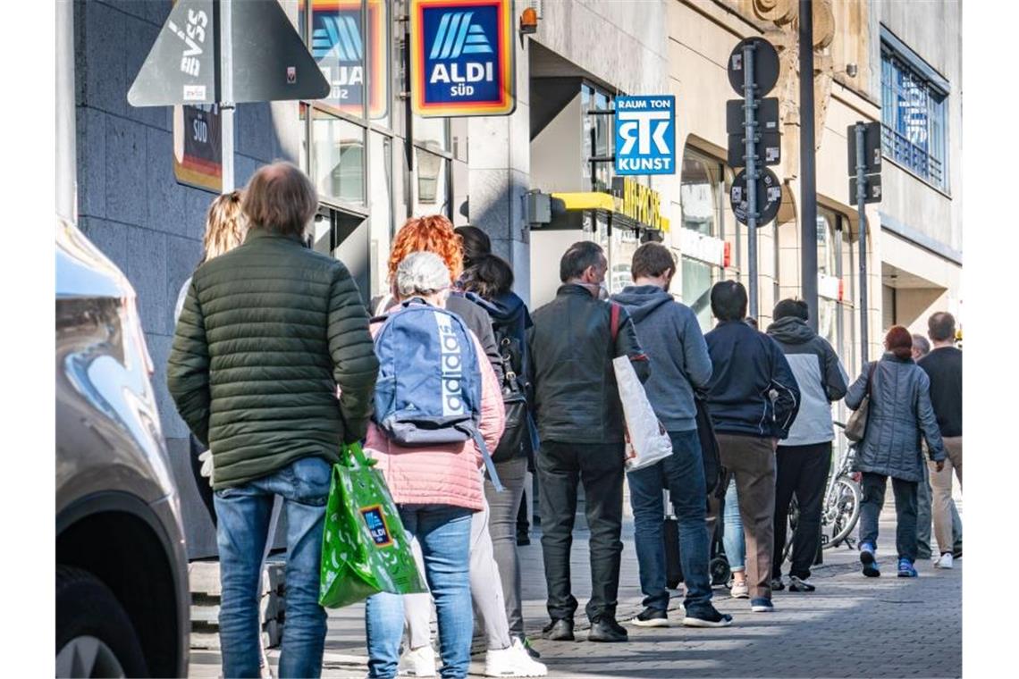 Kleine Geschäfte öffnen wieder - Schulen erstmal nicht In einer langen Schlange warten Menschen in Frankfurt auf Einlass vor dem Geschäft eines Discounters in der Innenstadt. Foto: Frank Rumpenhorst/dpa
