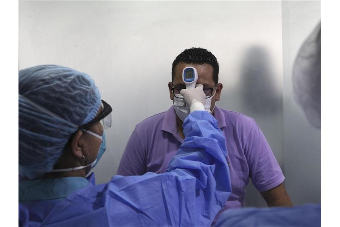 In einer medizinischen Station in Perus Hauptstadt Lima wird die Körpertemperatur eines Mannes gemessen. Foto: Martin Mejia/AP/dpa