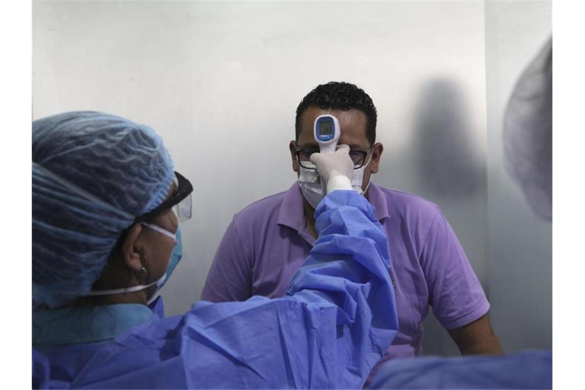 Coronavirus: Kanzlerin Merkel ruft alle zur Solidarität auf In einer medizinischen Station in Perus Hauptstadt Lima wird die Körpertemperatur eines Mannes gemessen. Foto: Martin Mejia/AP/dpa