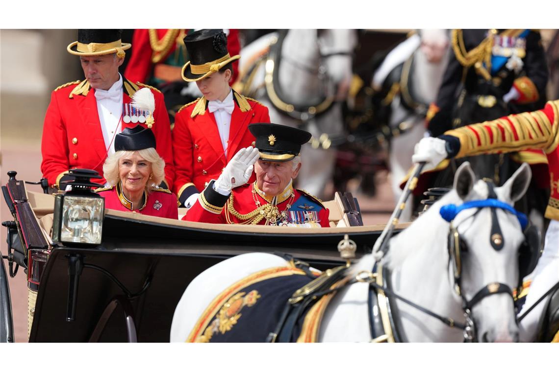 In einer offenen Kutsche fährt das britische Königspaar durch London.