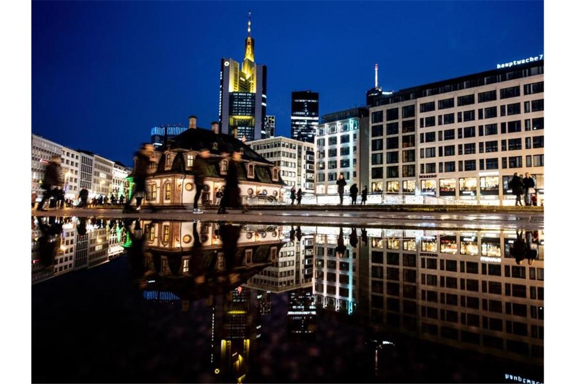 In einer Pfütze spiegeln sich die Hauptwache und die Skyline von Frankfurt. Foto: Boris Roessler/dpa/Archiv