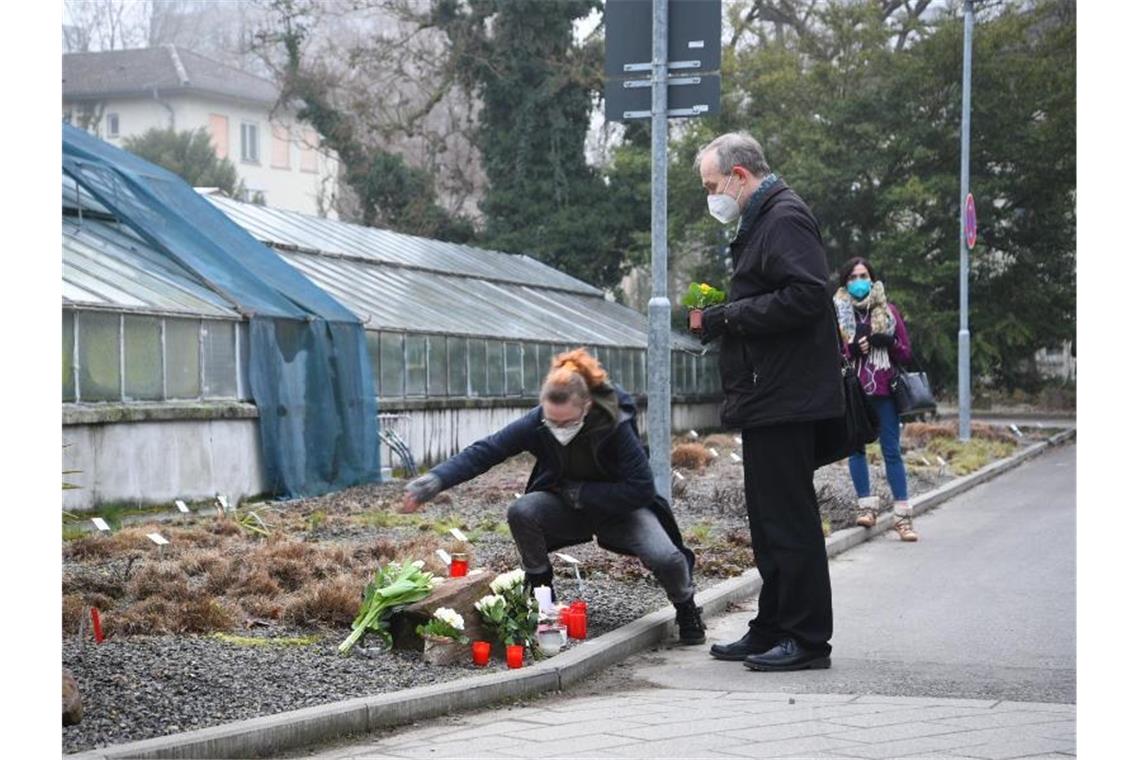 Protokoll der Panik - Ermittler suchen nach Motiv In Gedenken an die Toten: Ein Frau und ein Mann legen auf dem Gelände der Heidelberger Universität Blumen nieder. Foto: R.Priebe/Pr-Video/dpa