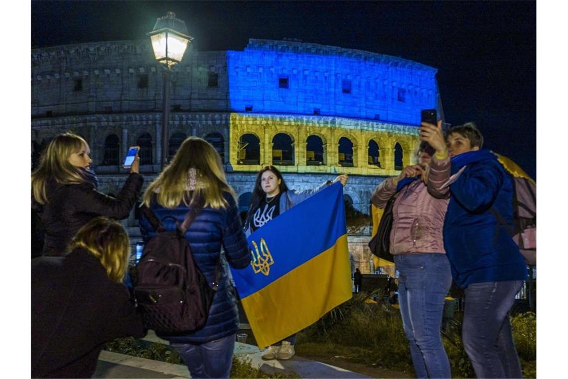Immer mehr Russen rufen zur Beendigung des Krieges auf In Italien lebende ukrainische Staatsangehörige stehen vor dem Kolosseum, das in den Farben der ukrainischen Nationalflagge beleuchtet ist. Foto: Domenico Stinellis/AP/dpa
