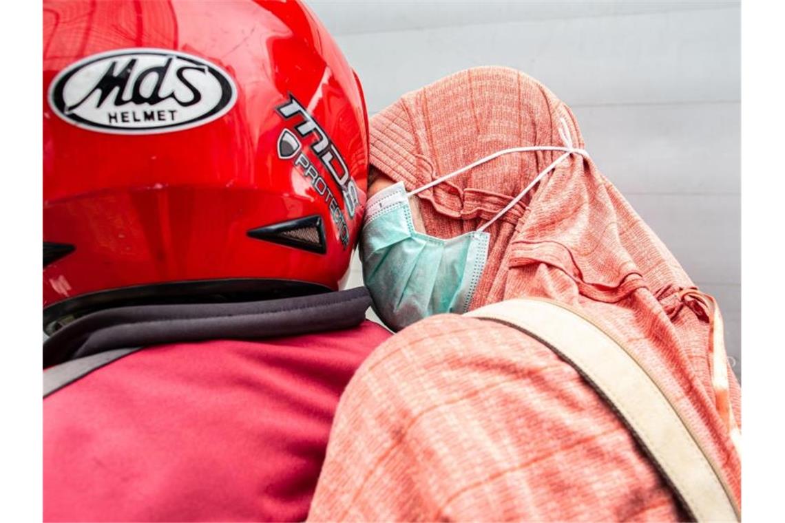 WHO erklärt Gesundheitsnotstand wegen Coronavirus In Jakarta trägt eine Frau als Beifahrerin auf einem Motorrad eine Atemschutzmaske. Foto: Donal Husni/ZUMA Wire/dpa