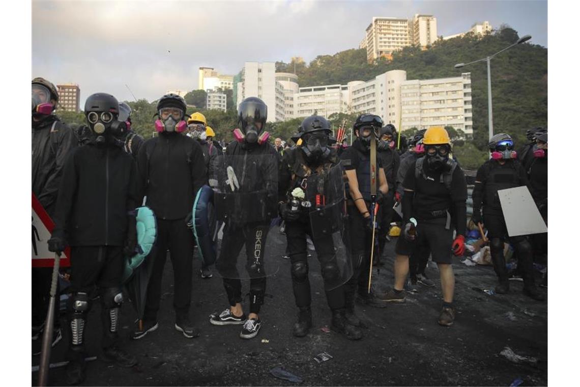 In Kampfmontur: Bewaffnete Studenten mit selbstgebauten Atemmasken vor eines Universität in Hongkong. Foto: Kin Cheung/AP/dpa