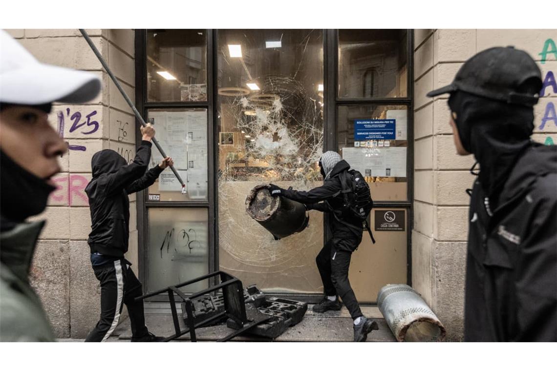 In Mailand versuchen Vermummte am Rande der Proteste in einen Laden einzudringen.