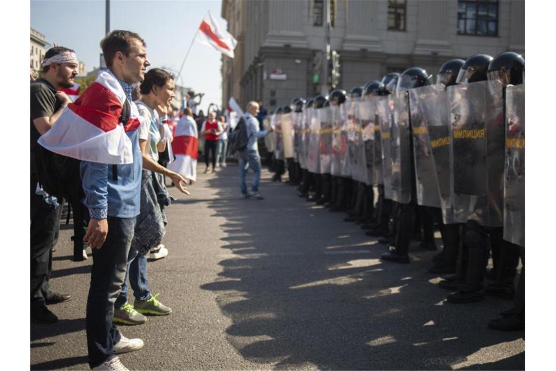 Lukaschenko kündigt erstmals Reformen für Belarus an In Minsk stehen sich Demonstranten mit der ehemaligen belarussischen Nationalflagge und Bereitschaftspolizisten gegenüber. Foto: ---/AP/dpa