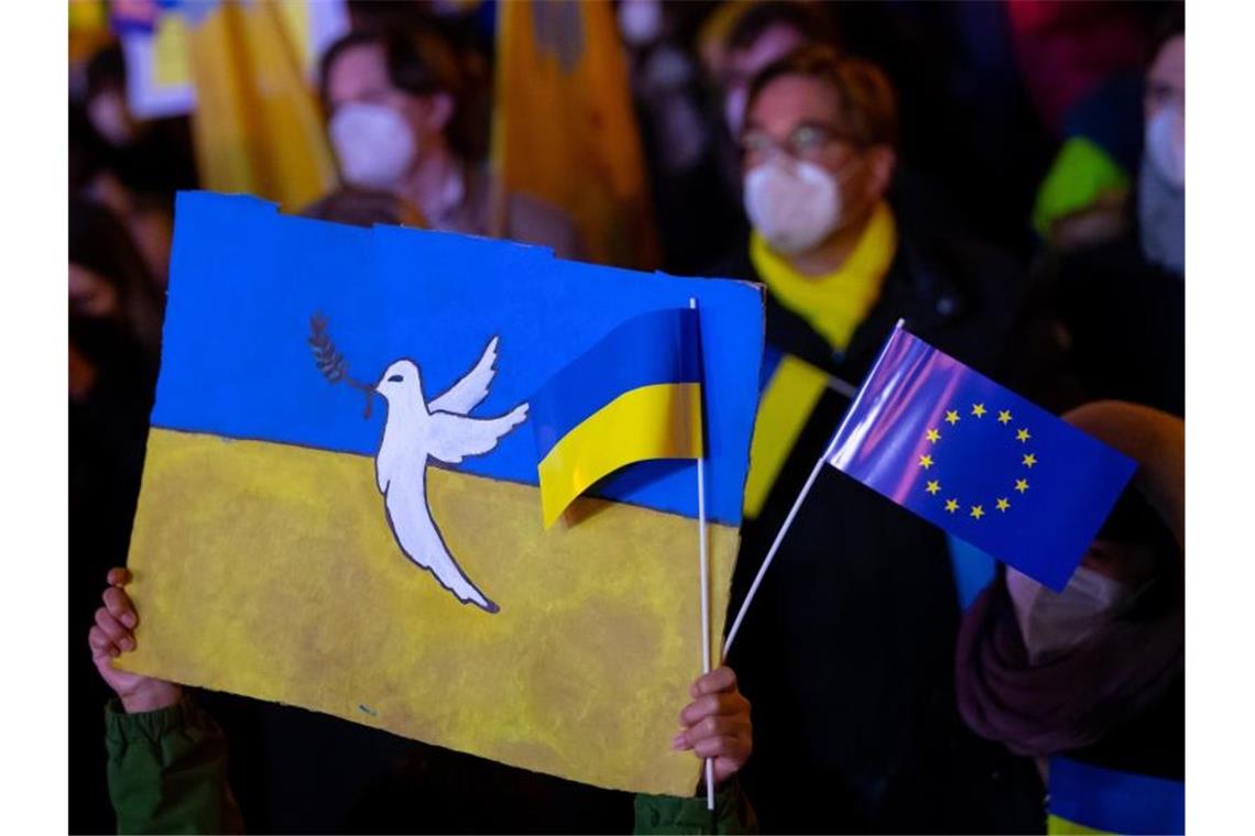 Thema Krieg am Küchentisch: „Die Angst gehört jetzt dazu“ In München hält ein Kind Schilder mit einer Friedenstaube und der Flagge der Ukraine in die Höhe. Foto: Sven Hoppe/dpa