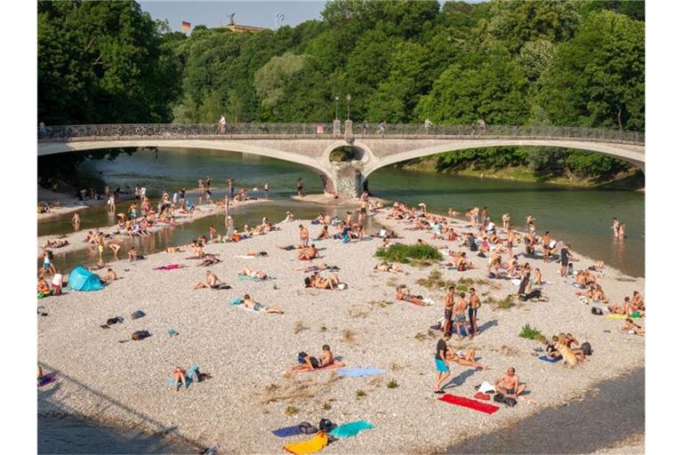 In München sonnen sich Badende auf einer Kiesbank in der Isar. Foto: Peter Kneffel