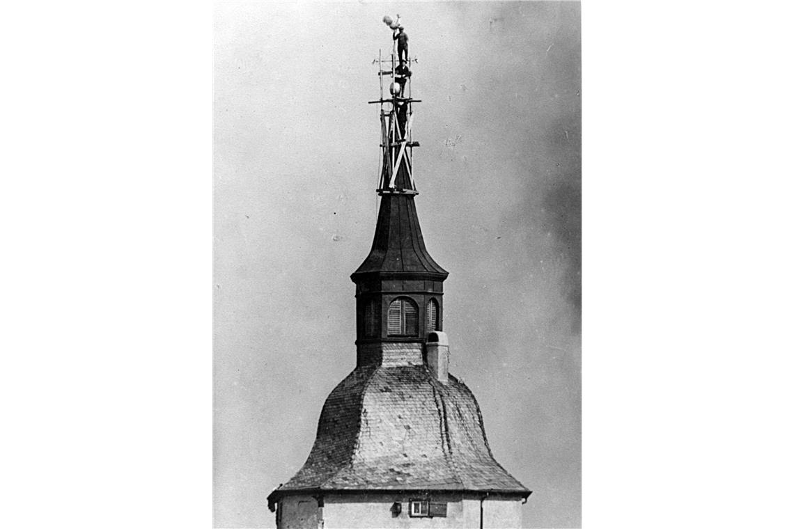 In schwindelnder Höhe befestigten Männer einen neuen Wetterhahn in den 1930er-Jahren.