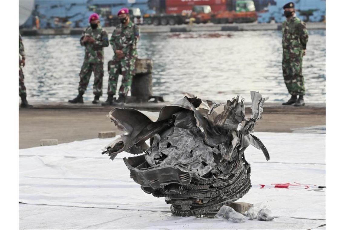 Indonesische Marinesoldaten betrachten ein großes Teil des abgestürzten Flugzeugs der Sriwijaya Air. Foto: Tatan Syuflana/AP/dpa