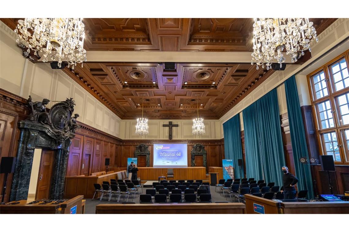 Innenansicht des historischen Saals 600 im Justizpalast Nürnberg, bekannt als zentraler Schwurgerichtssaal der Nürnberger Prozesse nach dem Zweiten Weltkrieg. Der Raum ist mit Holzvertäfelung, Kronleuchtern und grünen Vorhängen ausgestattet. 
