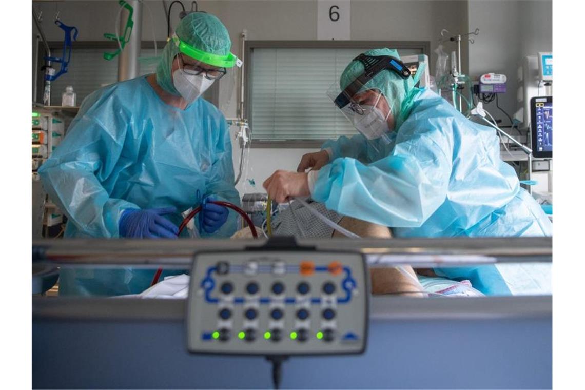 220.048 Corona-Neuinfektionen - Inzidenz sinkt weiter Intensiv-Pflegekräfte versorgen einen schwer an Corona erkrankten Patienten auf der Intensivstation des Klinikums in Fulda. Foto: Boris Roessler/dpa