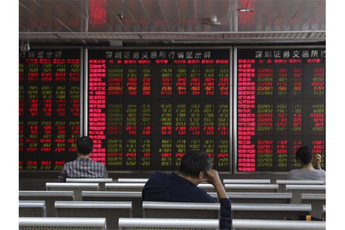 Investoren beobachten die Aktienkurse am Aktienmarkt. Vor Gesprächen zur Lösung des Handelskrieges zwischen den USA und China, den beiden größten Volkswirtschaften, rutschten die Aktien in Asien ab. Foto: Ng Han Guan/AP/dpa