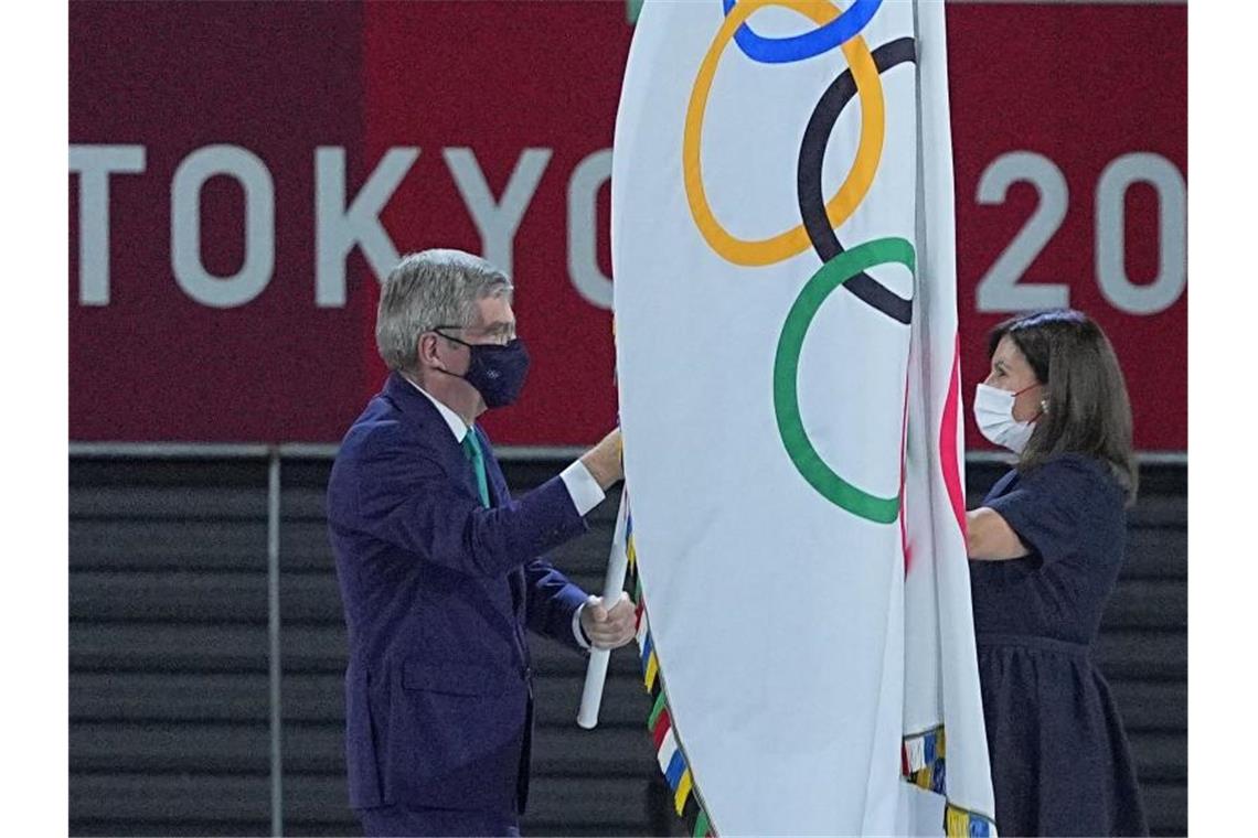 IOC-Chef Thomas Bach übergab die olympische Fahne an die Bürgermeisterin von Paris, Anne Hidalgo. Foto: Michael Kappeler/dpa