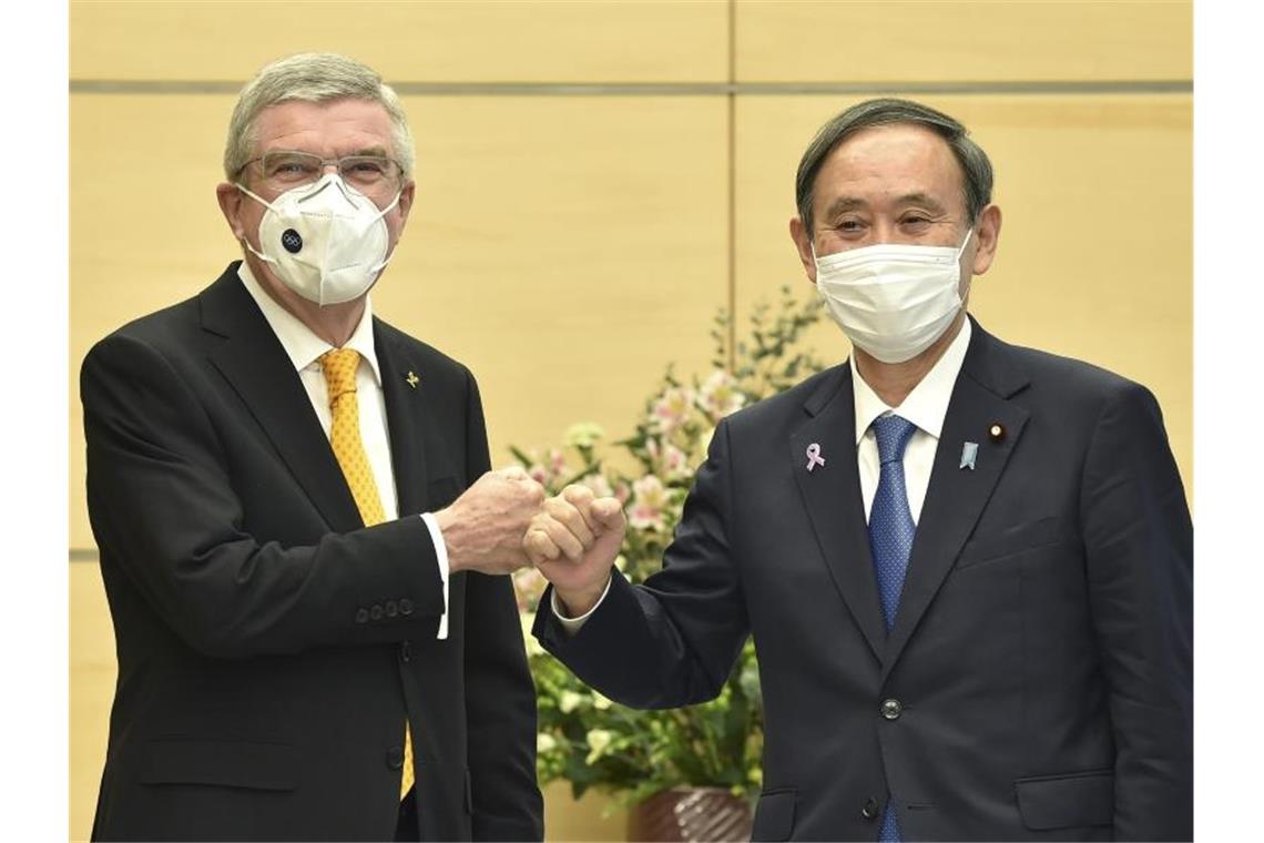 Tokio vor Ausnahmezustand - Olympia-Macher bleiben unbeugsam IOC-Präsident Thomas Bach (l) und Japans Premierminister Yoshihide Suga begrüßen sich. Foto: Kazuhiro Nogi/Pool AFP/AP/dpa