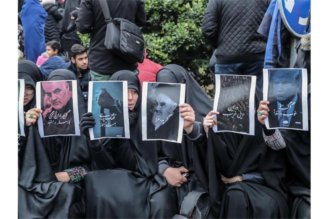 Iranische Frauen halten heim Trauerzug in Teheran Fotos hoch, auf denen unter anderen Ghassem Soleimani, Ruhollah Chomeini und Donald Trump abgebildet sind. Foto: Saeid Zareian/dpa