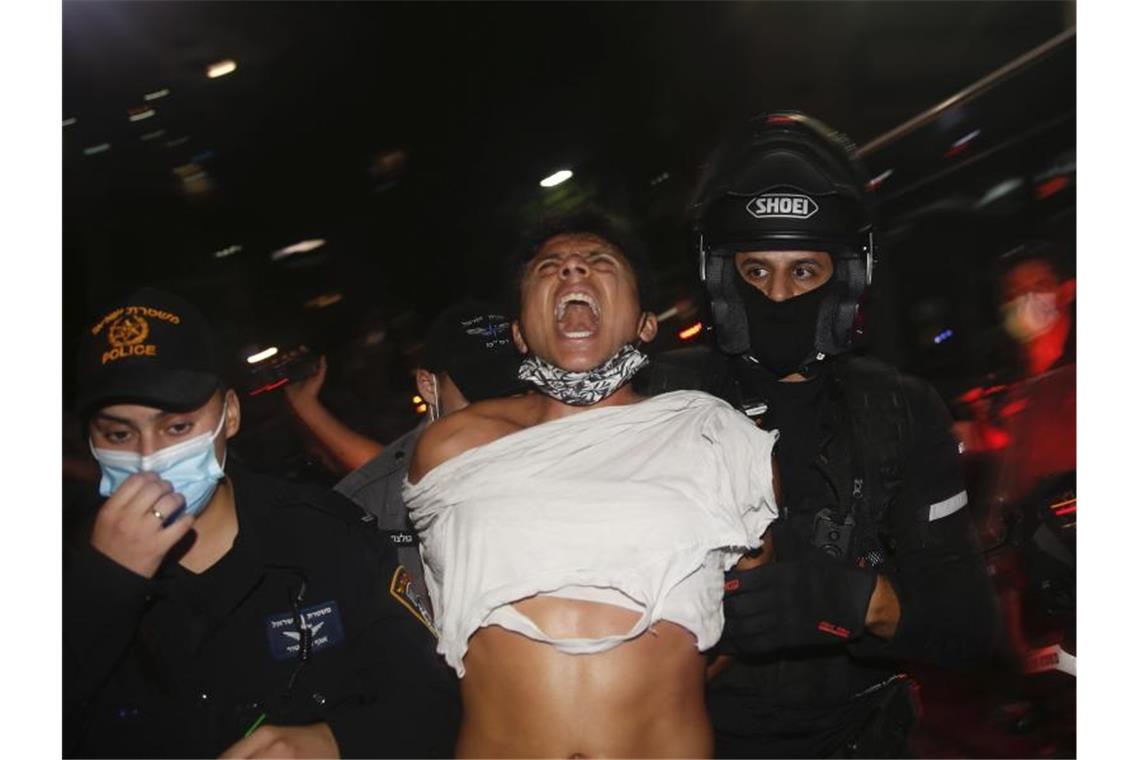 Israelische Polizeibeamte verhaften einen Demonstranten bei einem Protest gegen Sperrmaßnahmen, die ihrer Meinung nach darauf abzielen, die Proteste gegen Israels Premierminister Netanjahu einzudämmen. Foto: Ariel Schalit/AP/dpa