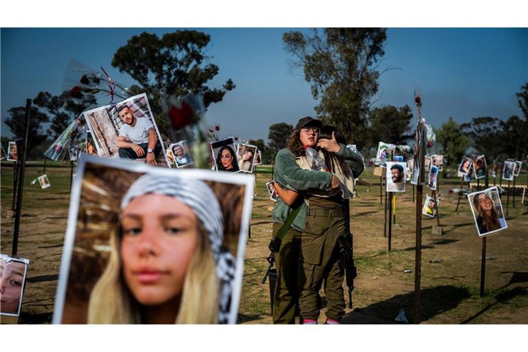 Israelische Soldatinnen stehen zwischen Fotos getöteter Israelis am Ort des Massakers beim Re'im-Musikfestival in der Negev-Wüste.