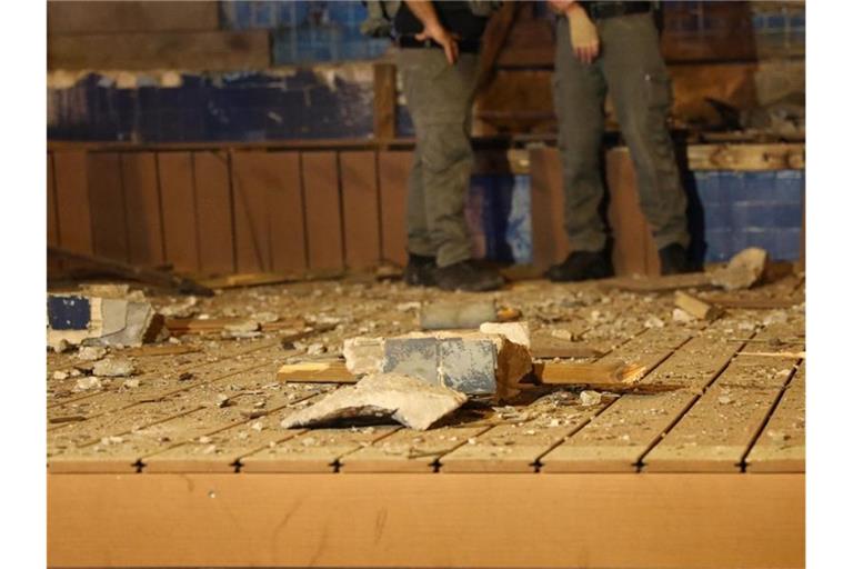 Isreaelische Polizisten stehen nach einem Raketenangriff aus dem Gazastreifen neben einer beschädigten Mauer. Foto: Ilia Yefimovich/dpa/Archiv