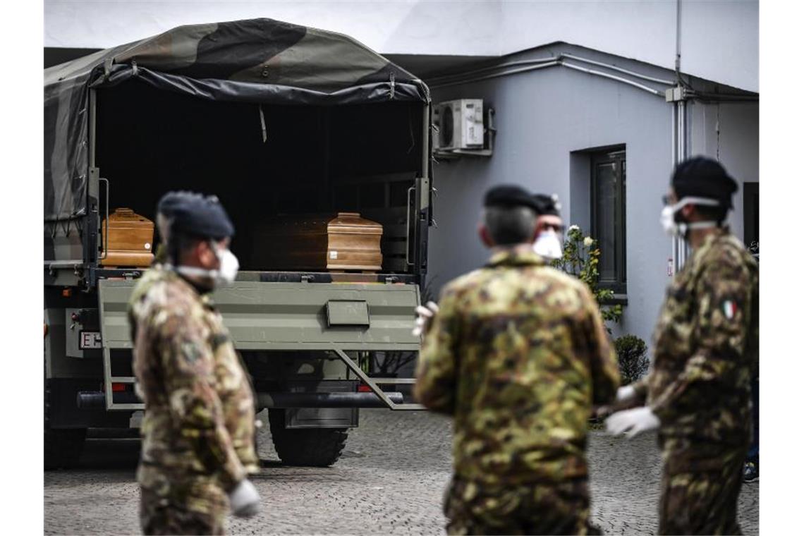 Italien meldet fast 1000 Corona-Tote an einem Tag Italienische Soldaten mit Mundschutz vor einem Militärfahrzeug mit Särgen von Corona-Opfern. Foto: Claudio Furlan/LaPresse/AP/dpa