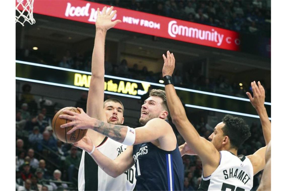 Ivica Zubac (l) und Landry Shamet (r) von den Los Angeles Clippers verteidigen unter dem Korb gegen Luka Doncic (M) von den Mavericks. Foto: Richard W. Rodriguez/AP/dpa