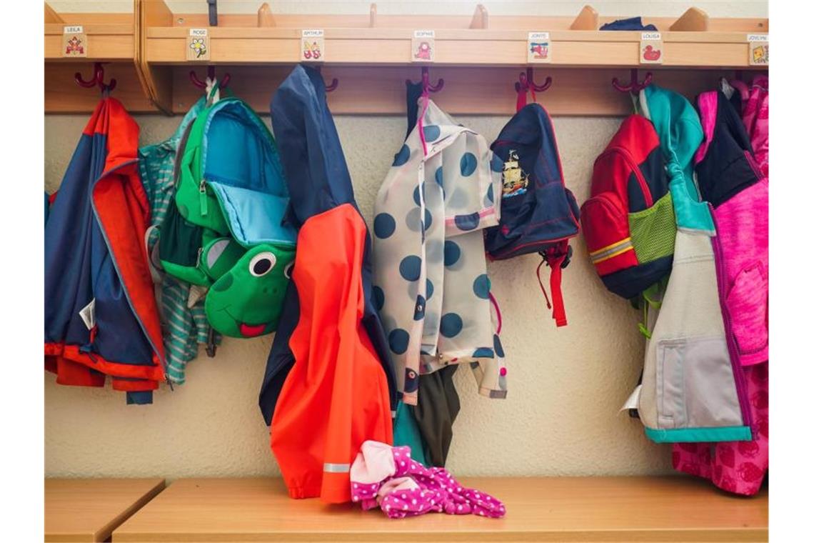 Jacken und Rucksäcke hängen an der Garderobe einer Kita. (Symbolbild). Foto: Jörg Carstensen/dpa