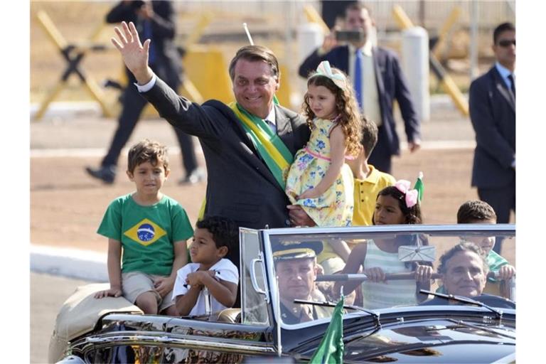 Jair Bolsonaro (M) kommt zu einer Flaggenhissungszeremonie in der Präsidentenresidenz. Foto: Eraldo Peres/AP/dpa