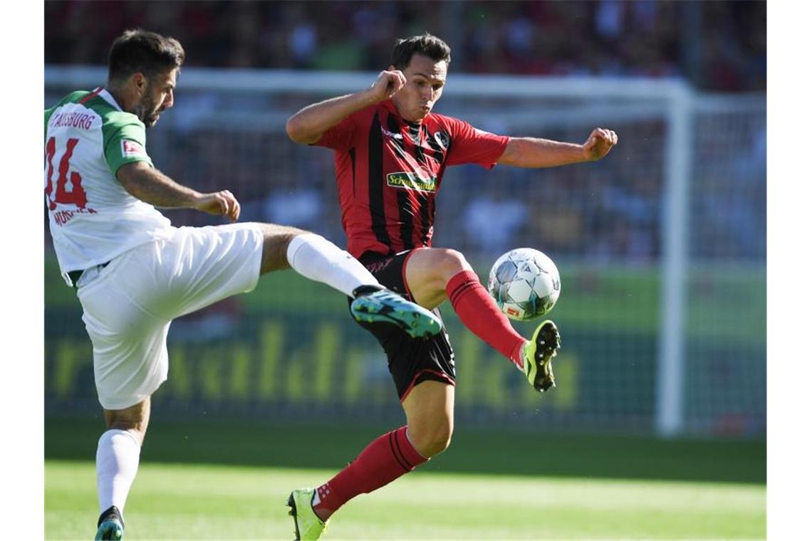 Jan Moravek (l) von Augburg versucht Nicolas Höfler (r) von Freiburg den Ball abzunehmen. Foto: Patrick Seeger