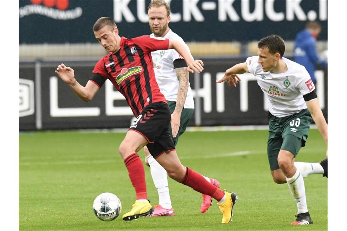 Janik Haberer (l) von Freiburg in Aktion gegen Kevin Vogt und Maximilian Eggestein (r) von Bremen. Foto: Thomas Kienzle/AFP-Pool/dpa/Archivbild