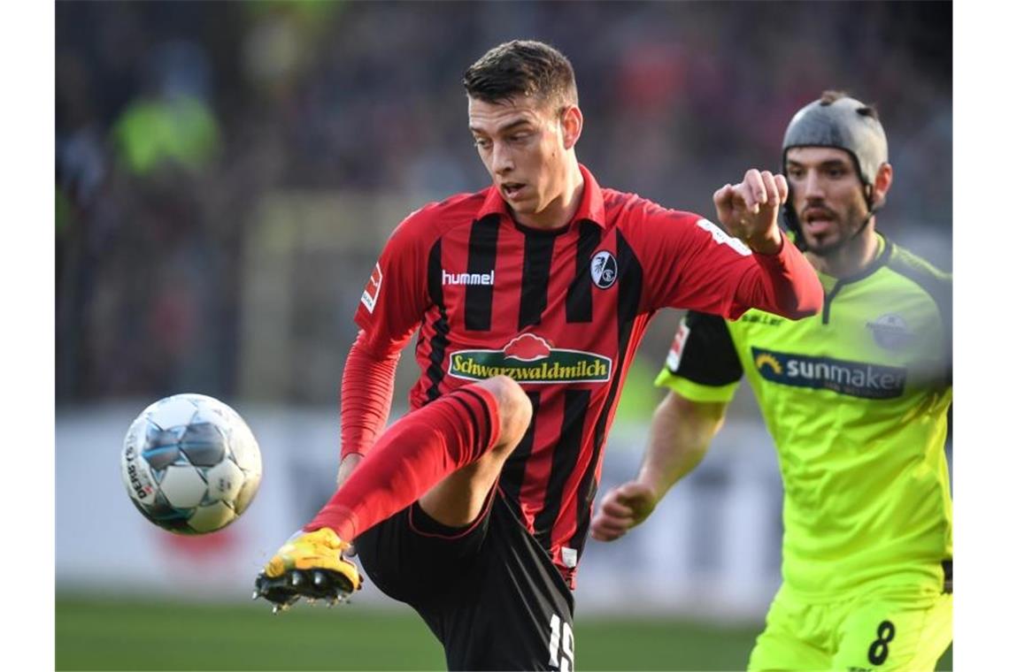 Janik Haberer von Freiburg (l) und Klaus Gjasula (r) von Paderborn kämpfen um den Ball. Foto: Patrick Seeger/dpa/Archiv