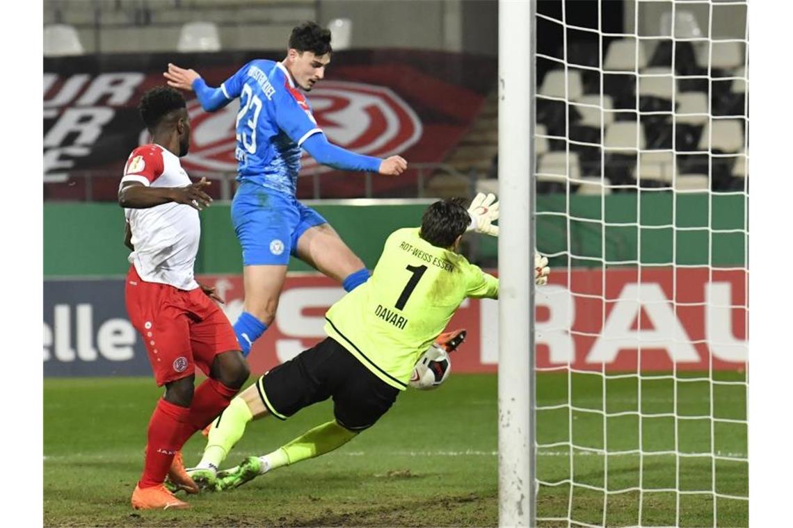 Elfmeter und Doppelschlag: Bayern-Schreck Kiel stoppt Essen Janni Serra (M) von Holstein Kiel erzielt gegen die Essener Daniel Heber (l) und Torwart Daniel Davari das Tor zur 2:0-Führung. Foto: Martin Meissner/AP POOL/dpa