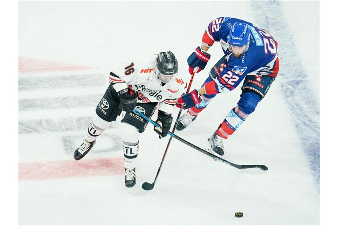 Jason Bast (l) und Matthias Plachta kämpfen um den Puck. Foto: Uwe Anspach/dpa/Archivbild