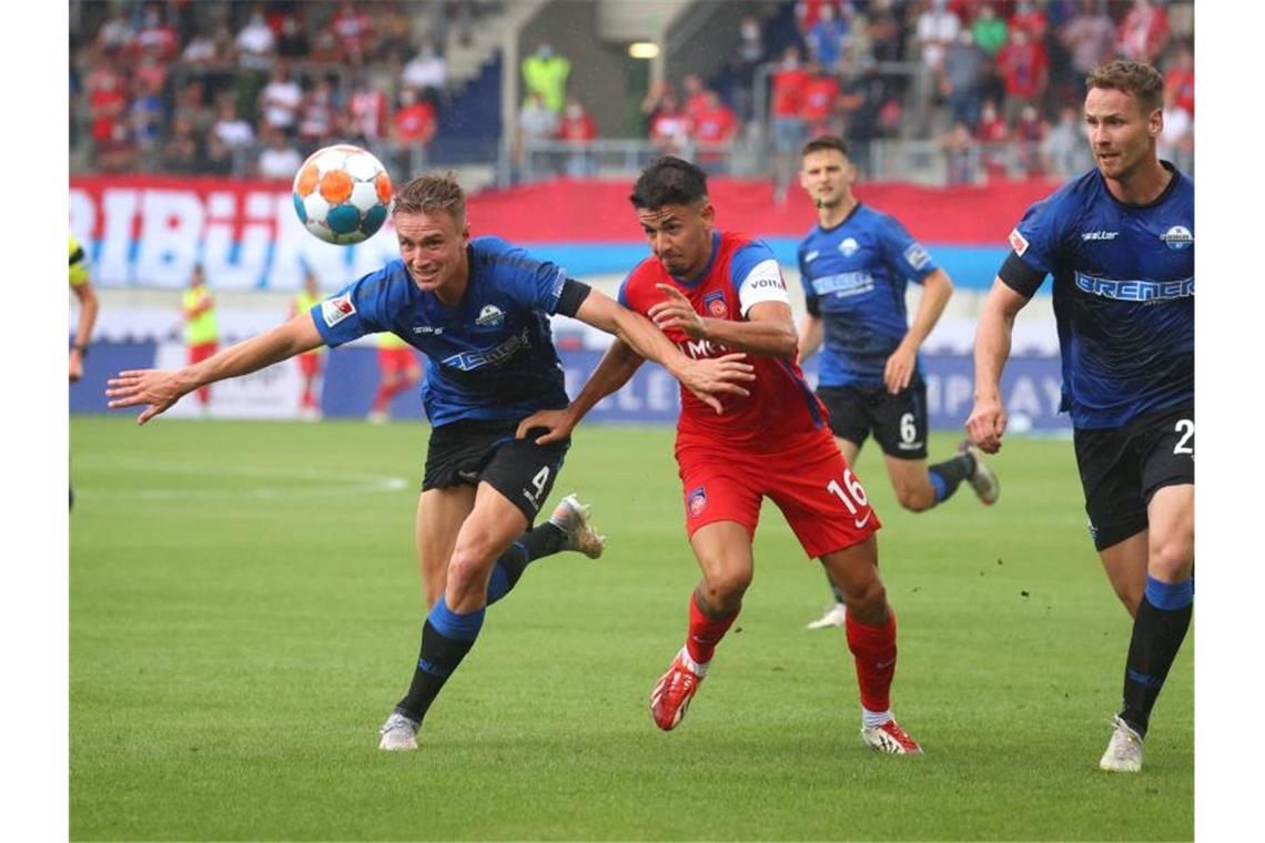 Jasper van der Werff (l) von Paderborn und Kevin Sessa von Heidenheim kämpfen um den Ball. Foto: Karl-Josef Hildenbrand/dpa