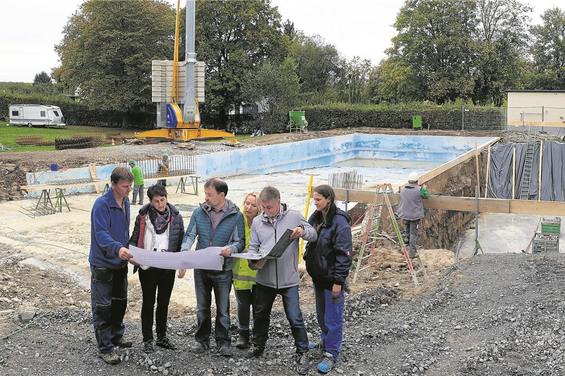 Jede Woche treffen sich die Verantwortlichen auf der Bädle-Baustelle in Erbstetten (von links): Wassermeister Antal Cserniczky, Bürgermeisterin Irmtraud Wiedersatz, Diplomingenieur Jochen Rausenberger vom Planungsbüro Richter+Rausenberger, Bauamtsleiterin Ursula Maierhöfer, Bauleiter Ralf Bauer und Schwimmmeisterin Jessica Bubeck. Im Hintergrund links ist der Teilabbruch des 33 Meter langen Beckens zu sehen. Rechts ist ein großes, vier Meter tiefes Loch ausgebaggert worden. Dort entsteht der Schwallwasserbehälter mit Pumpenraum. Die Bodenplatte ist bereits betoniert. Foto: F. Muhl