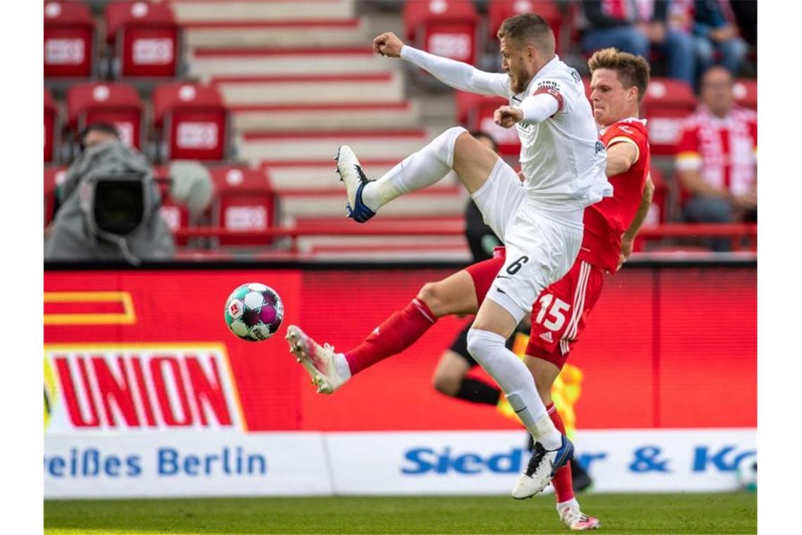 Jeffrey Gouweleeuw (l) vom FC Augsburg kämpft gegen Union-Spieler Marius Bülter um den Ball. Foto: Andreas Gora/dpa
