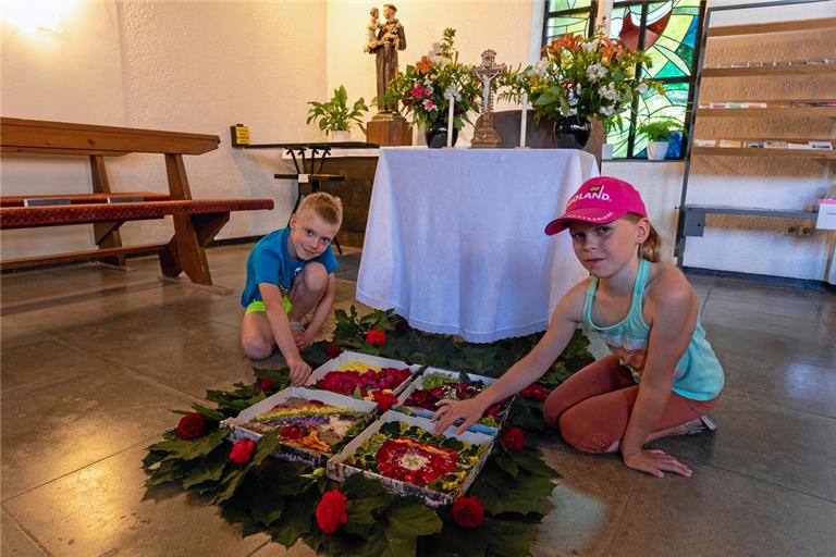 Jens und Diana Lutz haben ihre Pizzakartons für Fronleichnam mit kunstvollen Motiven gestaltet. Zum Abschluss des Fronleichnamsfests gab es für sie und alle Gemeindemitglieder noch Leckereien aus einem üppig gefüllten Korb an der Kirchentür.  Foto: Alexander Becher