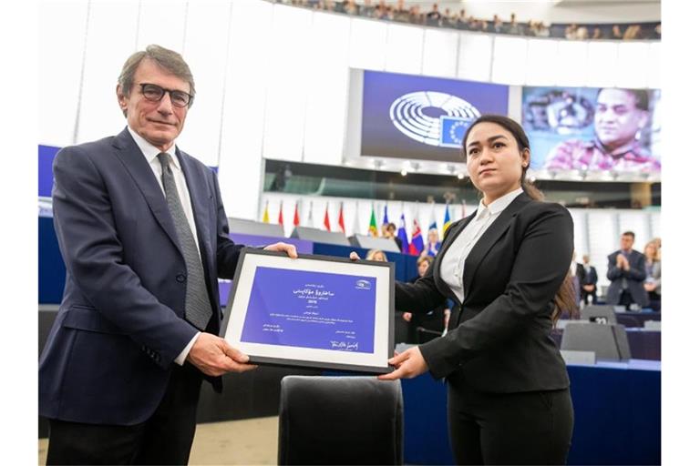 Jewher Ilham nimmt für ihren Vater den Sacharow-Preis aus den Händen des Präsidenten des Europäischen Parlaments, David Sassoli, entgegen. Im Hintergrund ist ein Foto von Ilham Tohti zu sehen. Foto: Philipp von Ditfurth/dpa