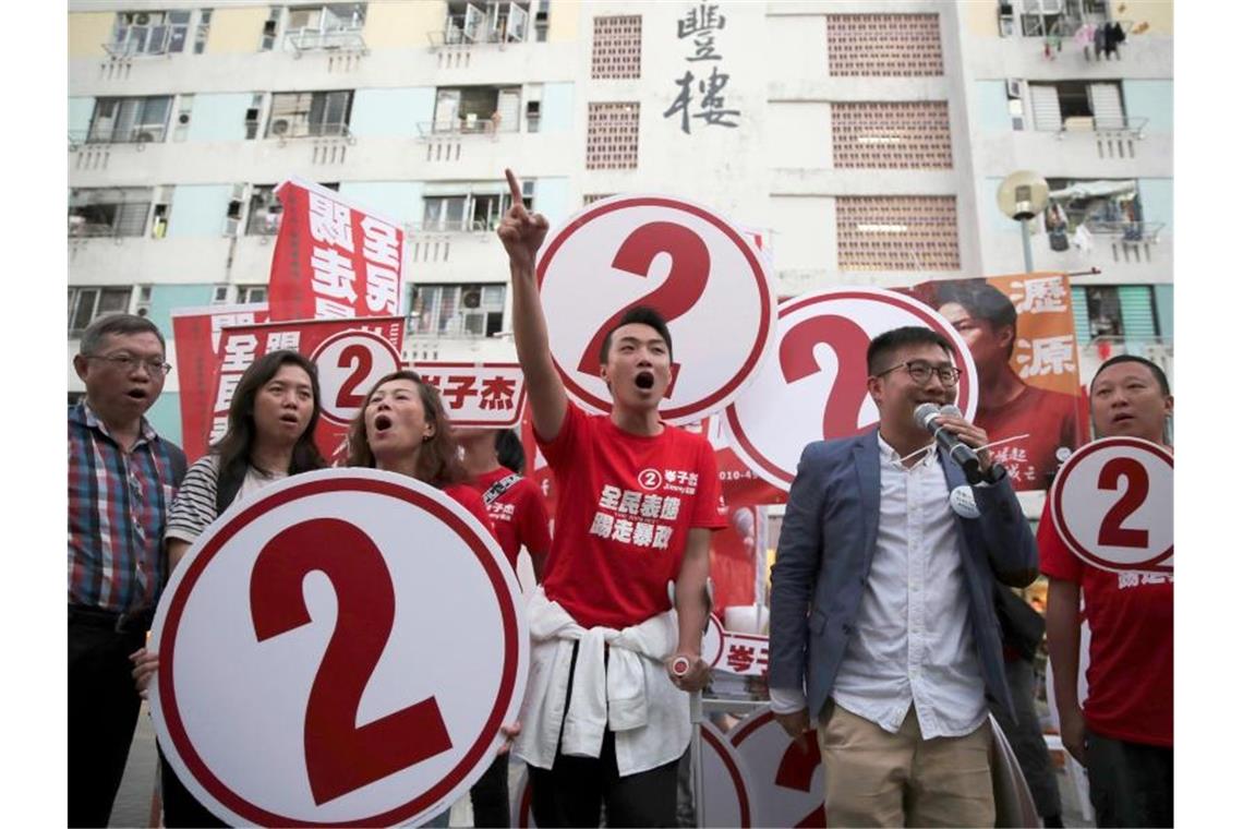 Hongkong: Demokratie-Lager liegt bei Bezirkswahlen vorn Jimmy Sham (M), regierungskritischer Aktivist, hält gemeinsam mit anderen Aktivisten Schilder für den Wahlkampf hoch. Foto: Kin Cheung/AP/dpa
