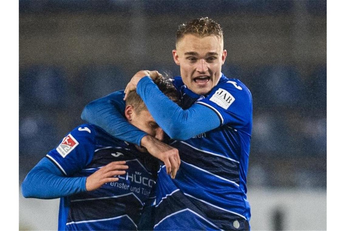 Joan Simun Edmundsson (l.) und Amos Pieper feiern die Herbstmeisterschaft von Arminia Bielefeld. Foto: David Inderlied/dpa