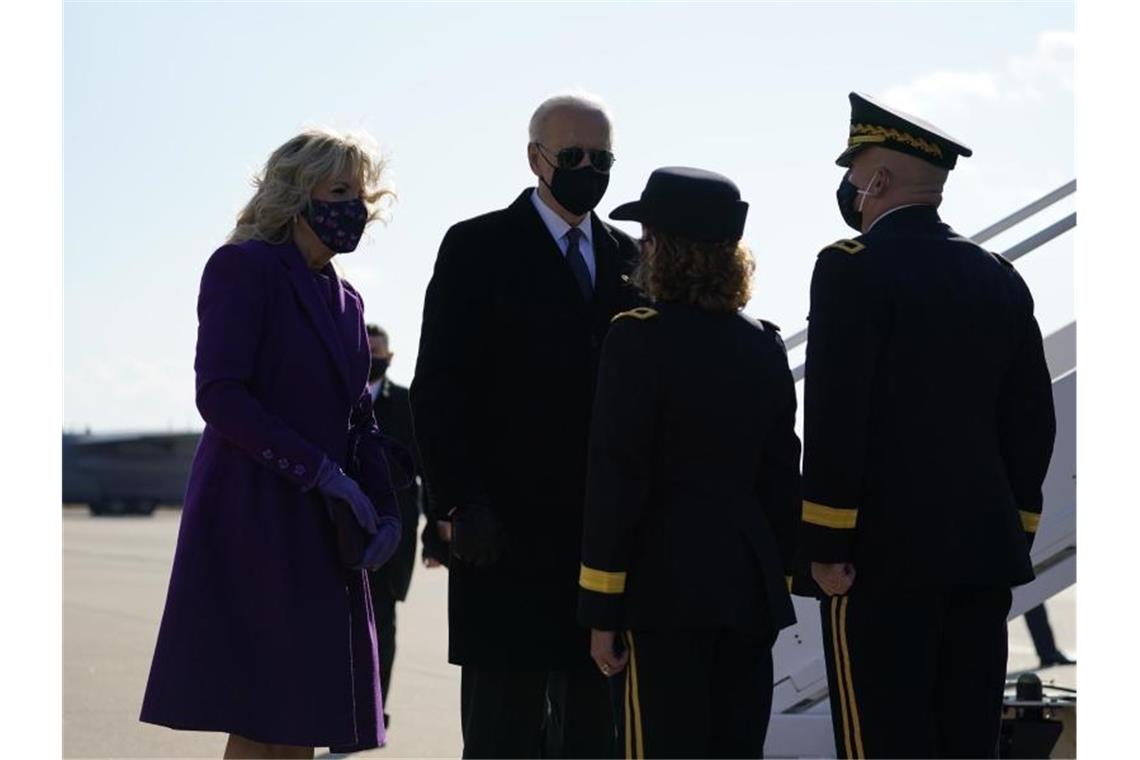Joe Biden (2.v.l), gewählter Präsident der USA, und seine Ehefrau Jill Biden (l), sprechen mit dem Flugpersonal als sie am Flughafen von New Castle ein Flugzeug besteigen. Foto: Evan Vucci/AP/dpa