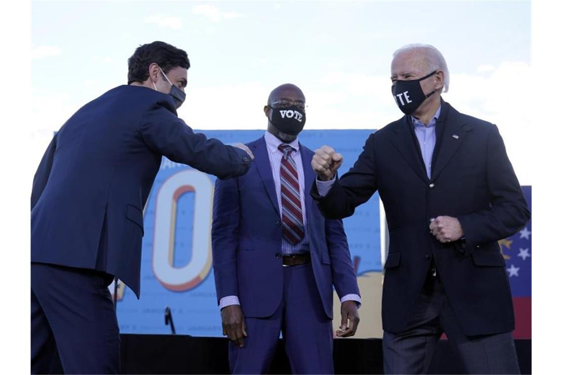 Entscheidende Stichwahlen zum US-Senat in Georgia begonnen Joe Biden (r) steht während einer Wahlkampfveranstaltung der demokratischen Kandidaten für den US-Senat mit Jon Ossoff (l) und Raphael Warnock auf der Bühne. Foto: Carolyn Kaster/AP/dpa