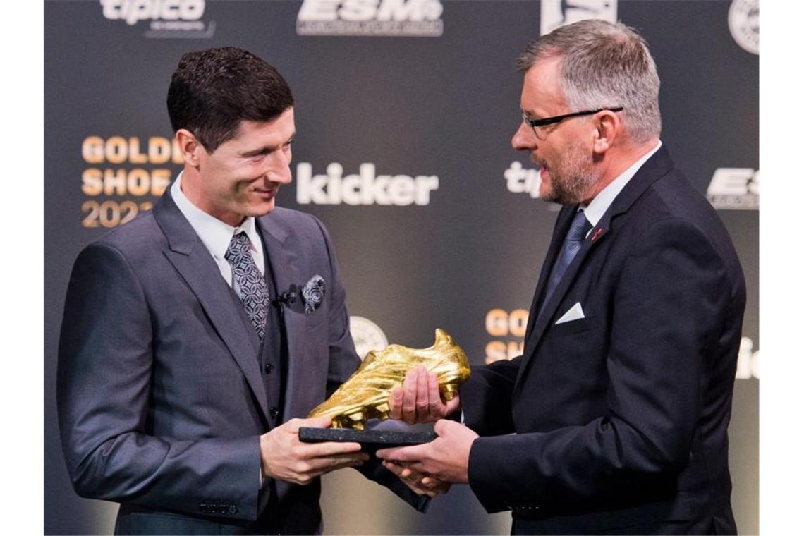 Jörg Jakob (r), Kicker-Chefredakteur, übergibt den Goldenen Schuh 2021 an Fußballprofi Robert Lewandowski. Foto: Michael Gottschalk/Kicker via picture alliance/dpa