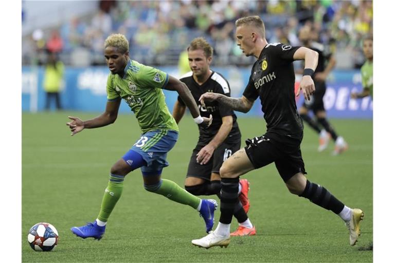 Joevin Jones von den Seaattle Sounders (l) wird von den BVB-Spielern Marius Wolf (r) und Mario Götze attackiert. Foto: Ted S. Warren/AP