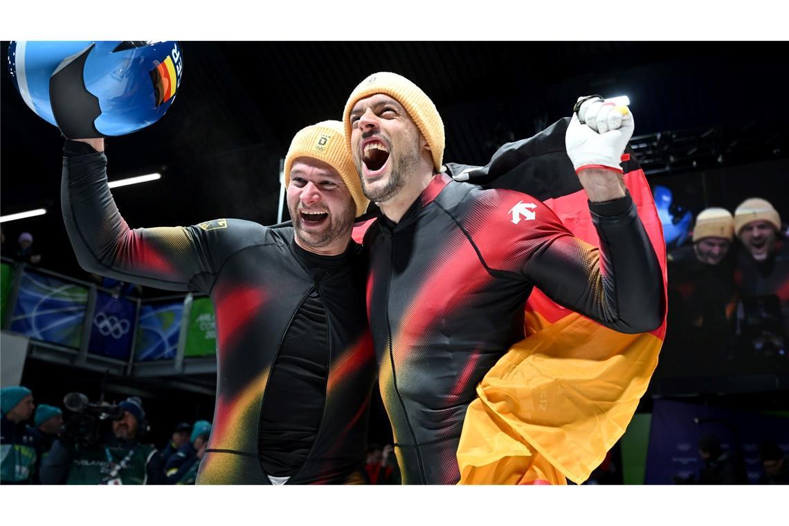 Johannes Lochner (Pilot, l) und Georg Fleischhauer bejubeln ihren ersten Platz im Zweierbob bei den Olympischen Winterspielen Mailand Cortina 2026.