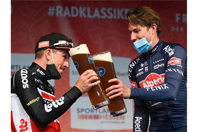 John Degenkolb (l) stößt mit Eschborn-Frankfurt-Sieger Jasper Philipsen an. Foto: Arne Dedert/dpa