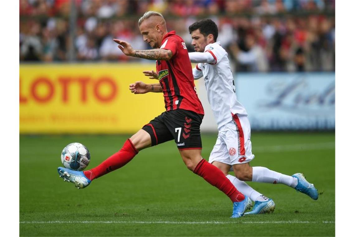 Jonathan Schmid von Freiburg und Karim Onisiwo von Mainz (l-r.) bemühen sich um den Ball. Foto: Patrick Seeger/Archivbild